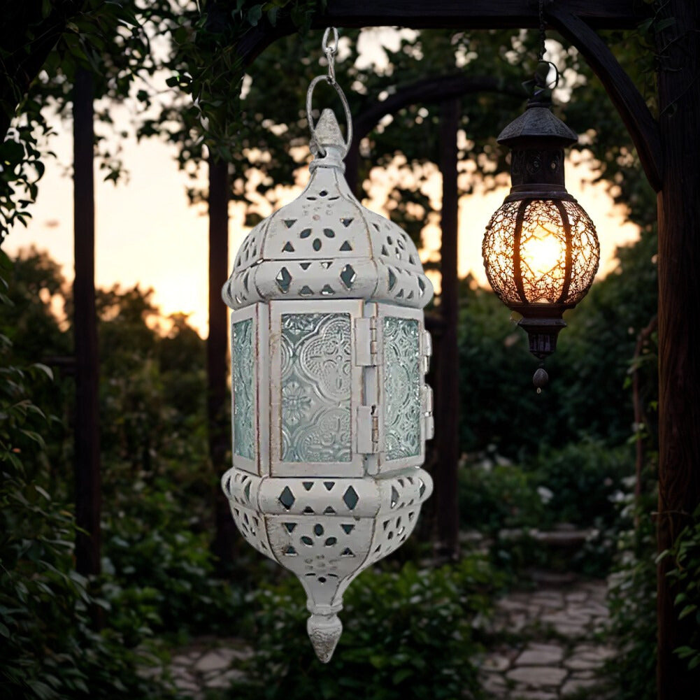 Hanglamp Baalbek – witte uitvoering met helder geperst glas en sierlijk metaalwerk, sfeervol in tuin bij zonsondergang